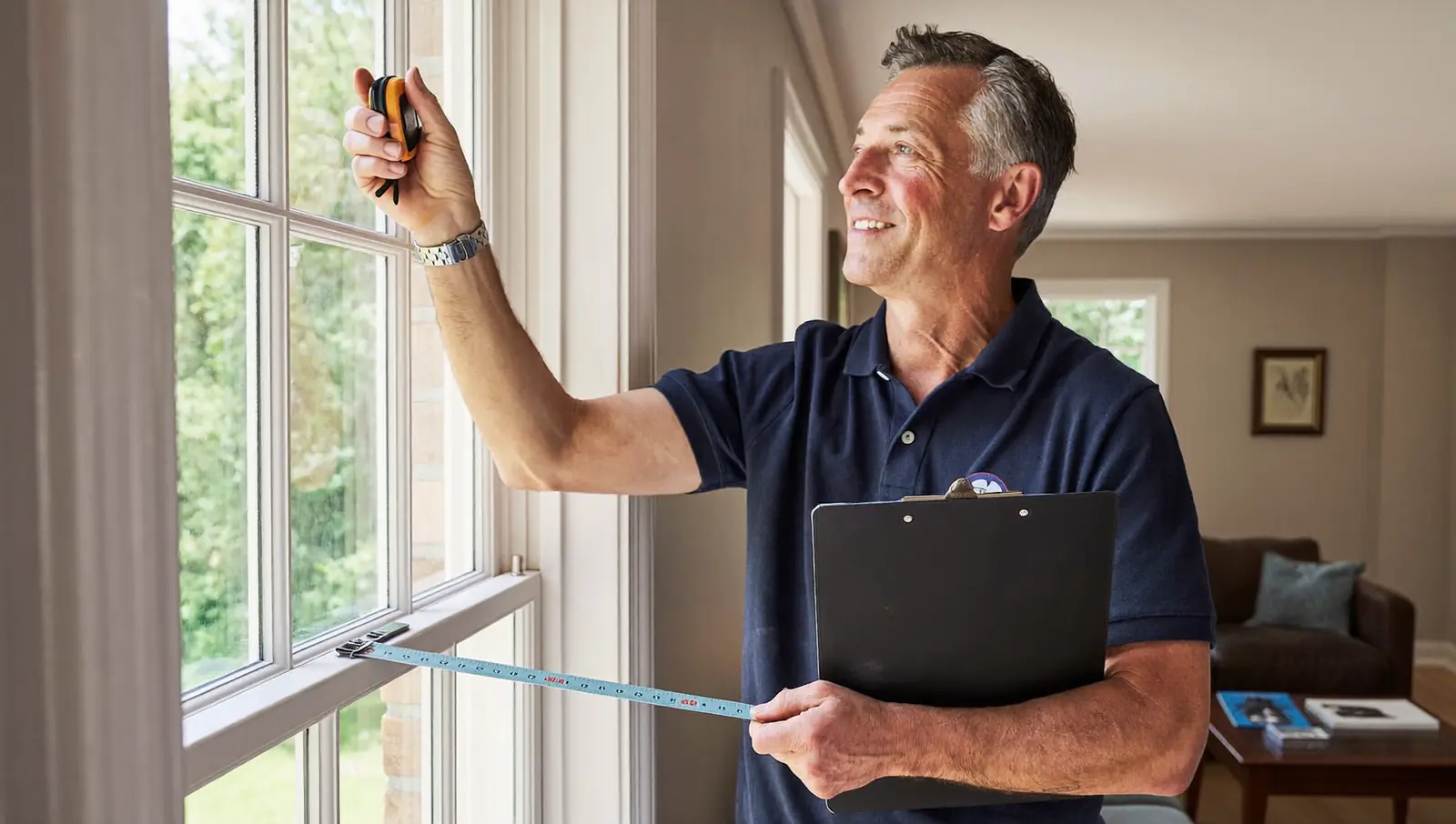 Surveyor measuring a living-room window to prepare a double glazing quote